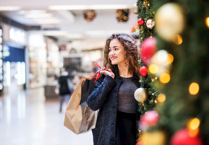 Jovem em um shopping com compras feitas em lojas de varejo.